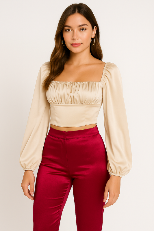 Woman wearing a beige top and red pants against a plain background