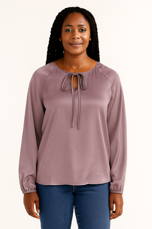 Woman wearing a mauve long-sleeve top with a tie neckline on a white background